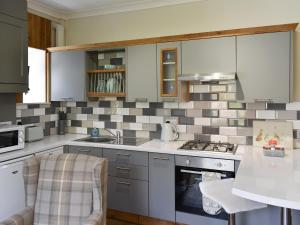 a kitchen with a sink and a stove at Slant End Cottage in Golcar +8 photos