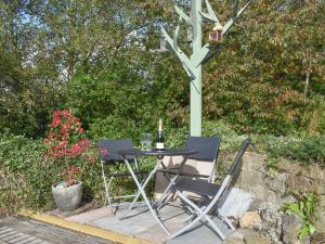 a table with two chairs and a bottle of wine at Slant End Cottage in Golcar