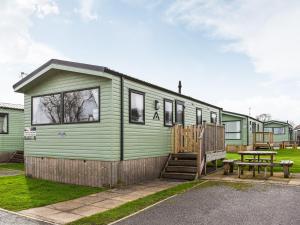 a green tiny house with a bench and a table at Brimham Retreat - Uk37641 in Knaresborough