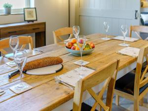 a wooden table with a bowl of fruit and wine glasses at Turnip Cottage in Newsham +21 photos