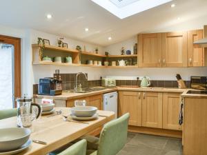 une cuisine avec des armoires en bois et une table avec des chaises dans l'établissement Logiemar Cottage, à Ballater 11 autres photos