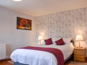 a bedroom with a large white bed with red pillows at Old Stables Cottage in Hunwick +11 photos