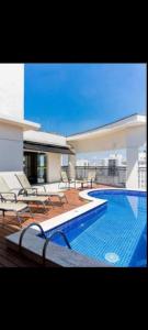 a swimming pool on a building with tables and chairs at Hotel Estanpla Moema Ibirapuera com garagem piscina 1004 in Sao Paulo