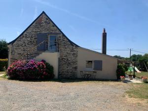 a small brick building with flowers in front of it at Gîte de la Bourrelière, Meublé de tourisme 3 étoiles in Le Louroux-Béconnais