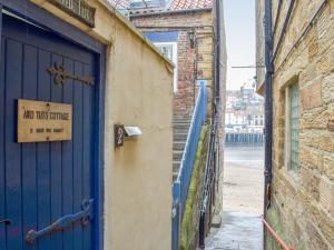 an alley with a blue door with a sign on it at Awd Tuts in Whitby