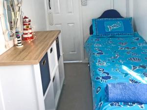 a small bedroom with a bed with a blue comforter at Driftwood in Mundesley +8 photos