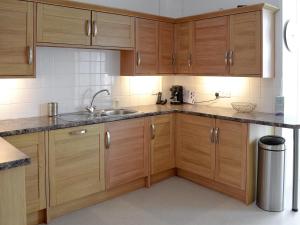 a kitchen with wooden cabinets and a sink at Seaglass in Marazion
