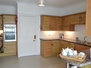 a kitchen with wooden cabinets and a white door at Seaglass in Marazion +9 photos