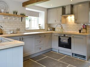 Una cocina con gabinetes blancos y un horno. en Grace Cottage, en Umberleigh Bridge