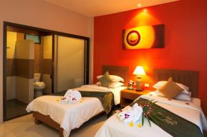 a hotel room with two beds and a red wall at Katanoi Resort in Kata Beach
