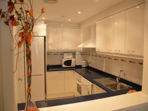 Una cocina con gabinetes blancos, un fregadero y un microondas. en Estartit Park 1-1, en Torroella de Montgrí
