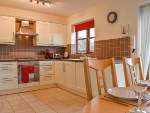 eine Küche mit weißen Schränken und einem Tisch und einer Spüle in der Unterkunft Ammonite Cottage in Whitby + 16 Fotos