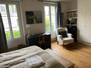 a bedroom with a bed and a chair and windows at Country house in Paris in Boulogne-Billancourt