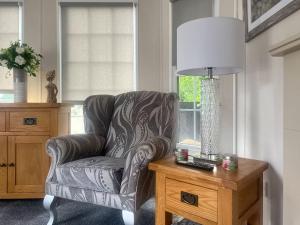 a living room with a chair and a lamp on a table at Meadows Farm Lodge - Uk47614 in Gorseinon