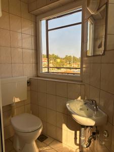 a bathroom with a toilet and a sink and a window at Apartments Renato in Vrboska