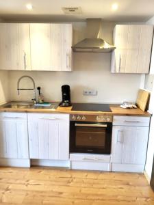 a kitchen with white cabinets and a sink and a stove at Ferienwohnung Zum Hochgrat in Oberstaufen +10 photos