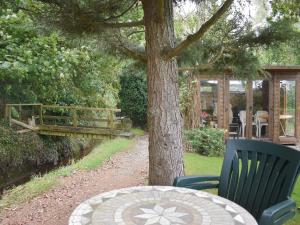 einen Tisch und einen Stuhl neben einem Baum in der Unterkunft Mill Cottage, Marsh Mills in Aveton Gifford