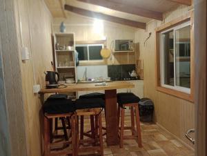 a small kitchen with a wooden table and stools at Cabañas Aliwen Lonquimay in Lonquimay