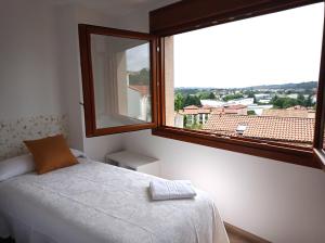 a bedroom with a bed and a large window at LAR SANTIAGO Apartamentos y Dúplex - Parejas, Familias y Peregrinos in Santiago de Compostela