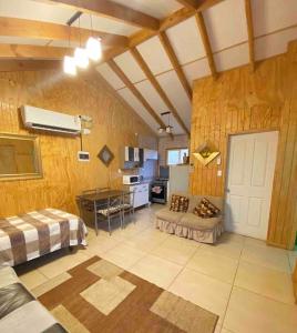 a large room with wooden walls and a kitchen at cabaña con tinaja refugio el mirador in Coihaique