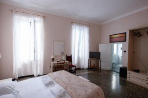 a bedroom with a bed and a desk and windows at Family Hotel Balbi in Genova