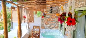a porch with a stone wall and a vase of flowers at Aliori art caves in Aegiali