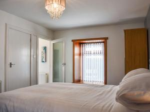 Un dormitorio con una cama grande y una ventana. en Belger Cottage, en Inverallochy