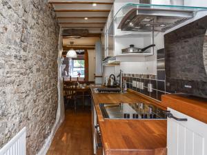 a kitchen with a stone wall and wooden counter tops at Greystones in Kirkby Stephen