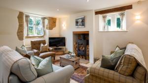 un salon avec deux canapés et une télévision dans l'établissement Pickett Cottage, à Hampnett