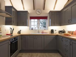 eine Küche mit grauen Schränken und einem Fenster in der Unterkunft Kingfisher Cottage in Wainfleet All Saints