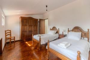 a bedroom with two beds and a wooden floor at Casa José & Maria, casa espaçosa para famílias e grupos até 10 pessoas in Braga