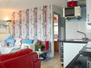 ein Wohnzimmer mit einem roten Sofa und einer Küche in der Unterkunft Woolacombe Folly in Mortehoe