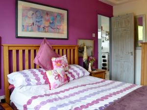 Schlafzimmer mit lila Wänden und einem Bett mit Kissen in der Unterkunft Woolacombe Folly in Mortehoe