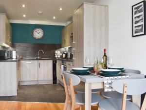 Una cocina con una mesa con sillas y un reloj en la pared. en Bankside, en Whitby