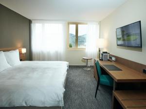 シュピーツにあるBelvédère Strandhotelの大きなベッドと机があるホテルの部屋