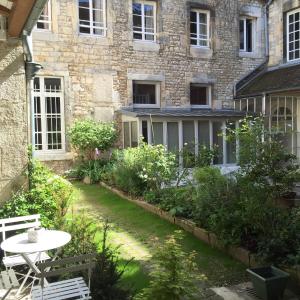 a garden with a table and chairs in front of a building at L'Annexe Apparthôtel du 11 D, 4 étoiles in Besançon