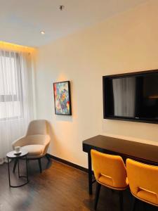a living room with a tv and a table and chairs at Căn hộ khách sạn Hạ Long Premier Sapphire in Ha Long