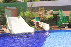 a slide in a swimming pool next to a swimming pool at Veredas do Rio Quente Family in Rio Quente
