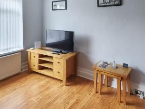 a television on a wooden stand with a table at Turtle's Nest in Newbiggin-by-the-Sea