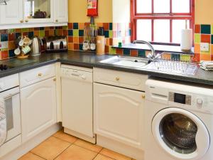 a kitchen with a sink and a washing machine at Cowslip - Uk12060 in Lower Boscaswell