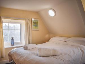 a bedroom with two beds and a window at Pump Cottage in Brancaster