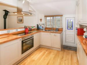 a kitchen with white cabinets and a wooden floor at Little Netherleigh in Trearddur