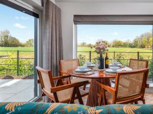 ein Esszimmer mit Tisch und Stühlen und einem großen Fenster in der Unterkunft Uk47693 - Piglet Cottage in Wimbish