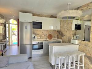 a kitchen with white cabinets and white stools at Apartment Orlando Torviscas Bajo in Adeje