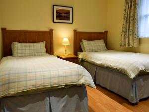 a bedroom with two beds and a lamp on a table at Inn Cottage in Glendevon +6 photos