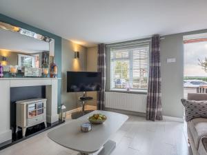 un salon avec une table et une cheminée dans l'établissement Riverside Cottage, à Reedham 32 autres photos