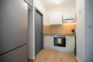 a small kitchen with white cabinets and a refrigerator at Au Petit Meuh'ster in Munster +14 photos