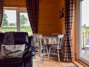 Un comedor con mesa y sillas y una ventana. en Pheasant Lodge - Uk33402, en Hungerton