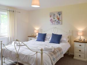 une chambre avec un lit blanc avec des oreillers bleus dans l'établissement Rose Farm Cottage, à Frostenden 3 autres photos