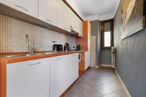 une cuisine avec des armoires blanches et un évier dans l'établissement Appartamento Il Campanile, à Tignale